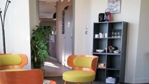 Een moderne wachtruimte met comfortabele zitplaatsen, een koffieapparaat en een boekenplank.