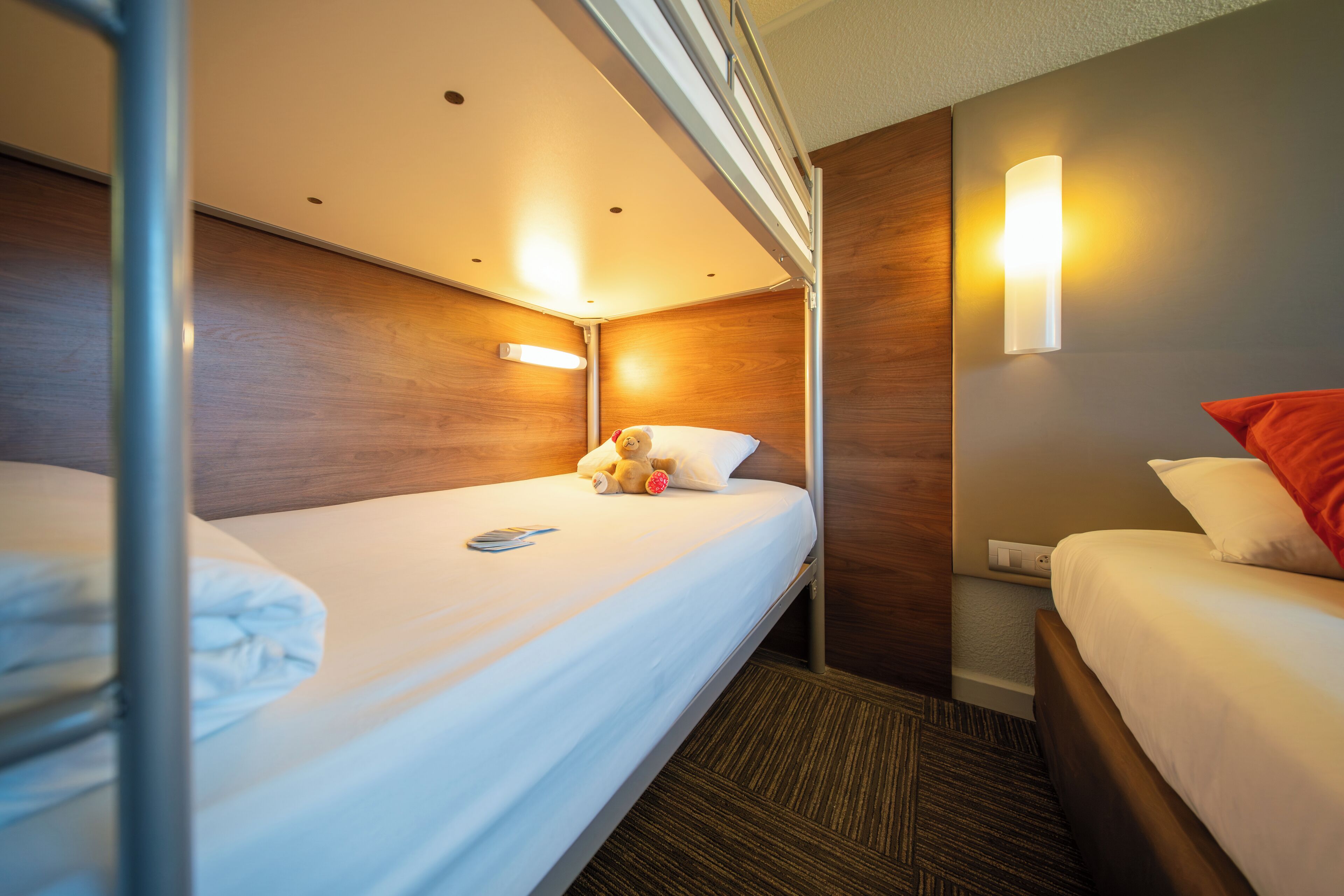 Ein Hotelzimmer mit zwei Betten, Holzvertäfelung, einer Wandleuchte und einer Steckdose.