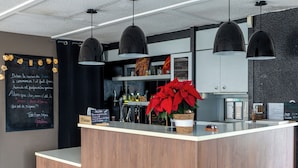 Een receptiegedeelte met een houten balie, zwarte hanglampen, een schoolbord met handgeschreven aantekeningen, en een kerststerrenplant.