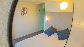 Ein Hotelzimmer mit einem Bett, zwei Kissen, einer Wandleuchte und einer Tür.