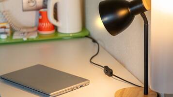 A laptop on a desk with a desk lamp and a power cord.