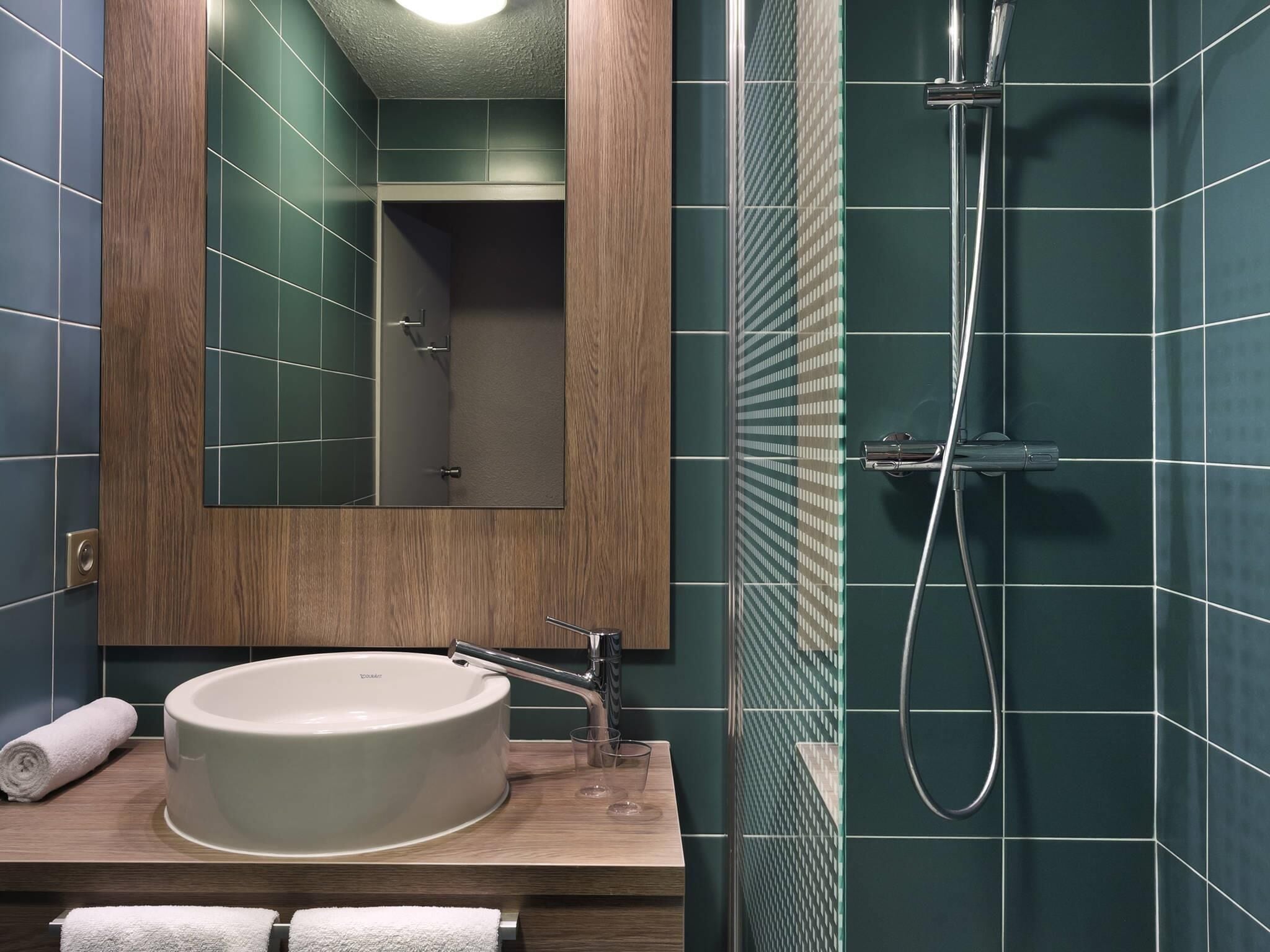 A modern bathroom with a large sink, a mirror, and a shower.
