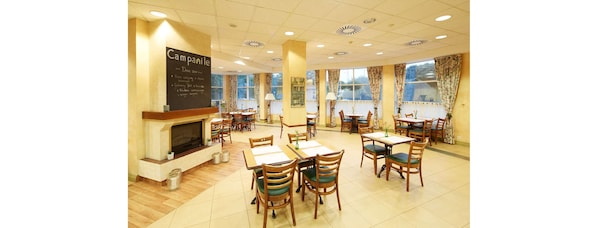 A dining area with tables and chairs, a fireplace, and a chalkboard menu.