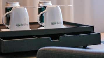 En bakke med to hvide krus med påskriften "Camparalle" og to dåser "Coca-Cola" på et bord.