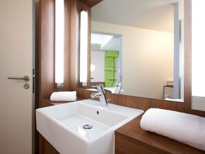 Un baño moderno con un lavamanos blanco, un espejo y paneles de madera.