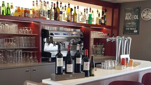 Una zona de bar con distintas botellas de licores, vasos y una máquina de café.