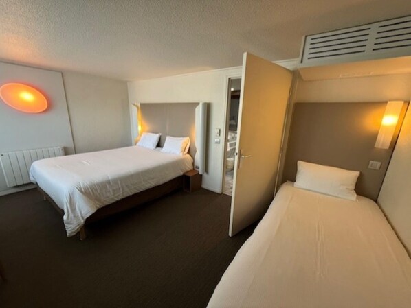 Une chambre d’hôtel avec deux lits, un radiateur et une porte donnant sur une salle de bain.