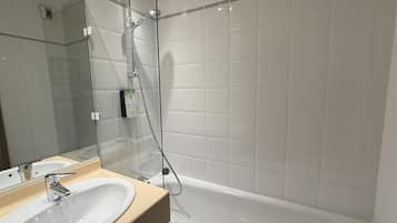 A modern bathroom with a glass shower enclosure, a white bathtub, and a beige vanity with a sink.