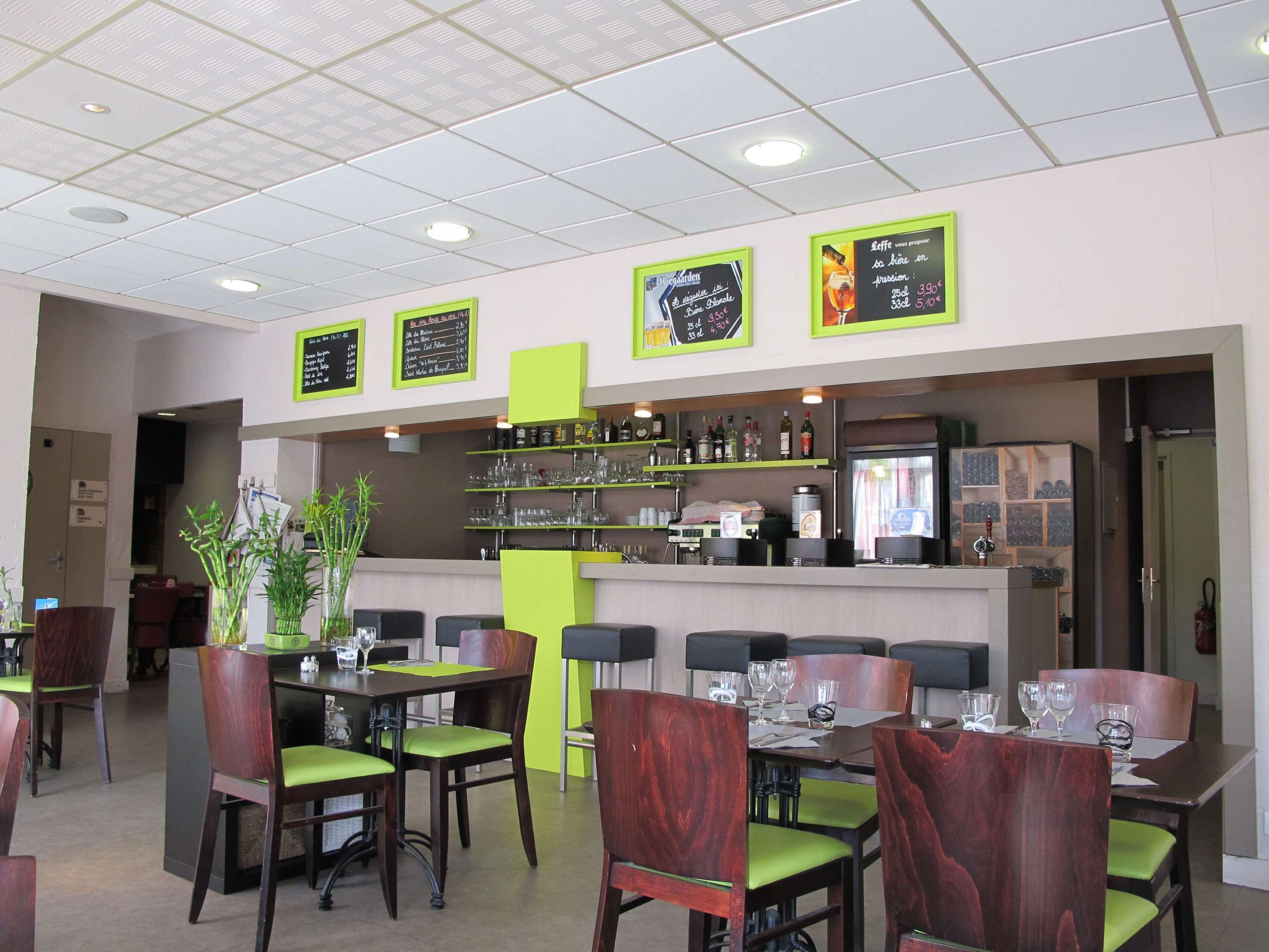 A restaurant interior with tables and chairs, a bar area, and menu boards on the wall.