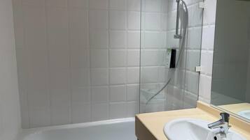 A bathroom with a bathtub, a sink, and a glass shower enclosure.