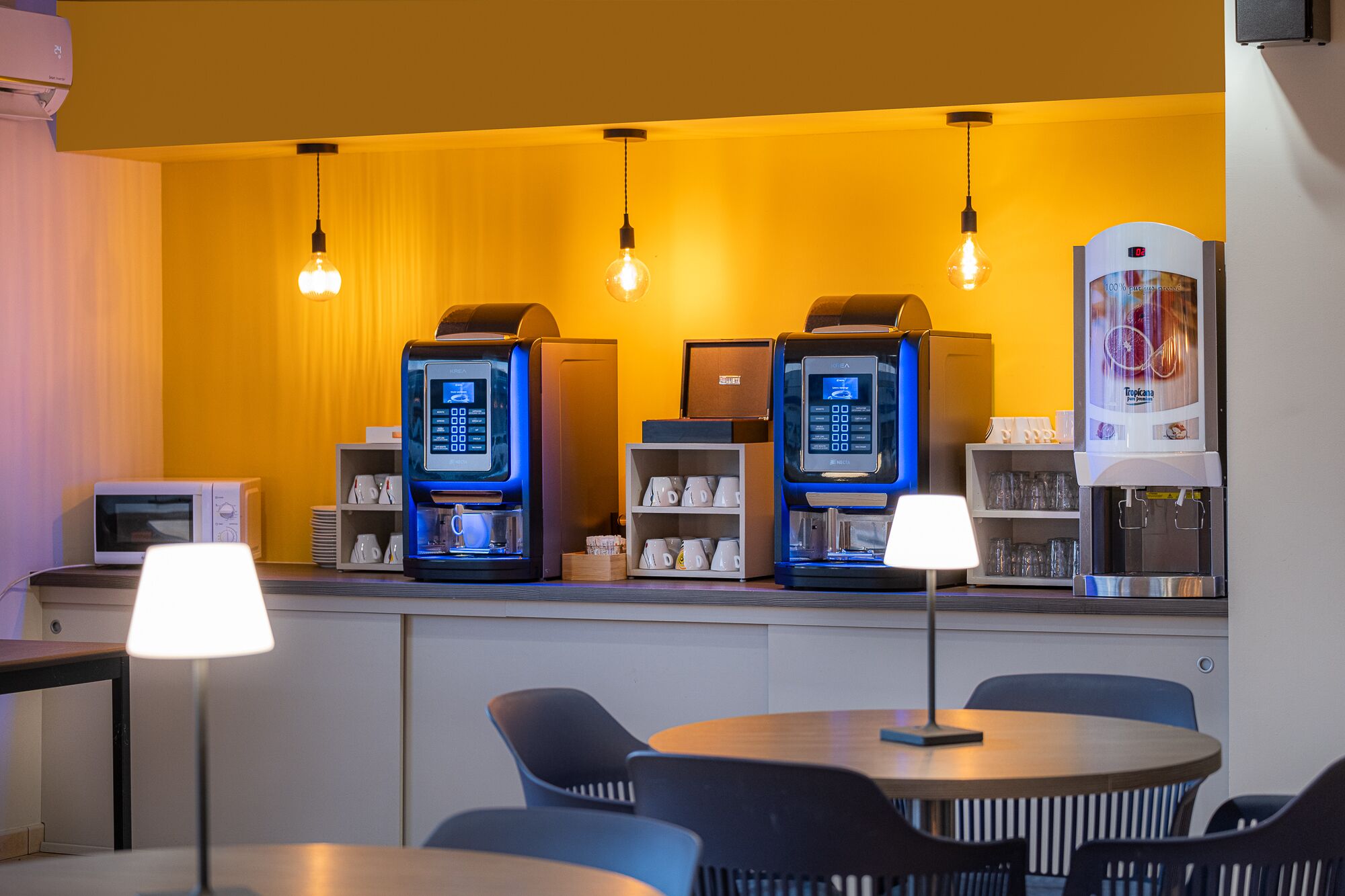 Quarto de hotel com cozinha compacta, cafeteira e micro-ondas.