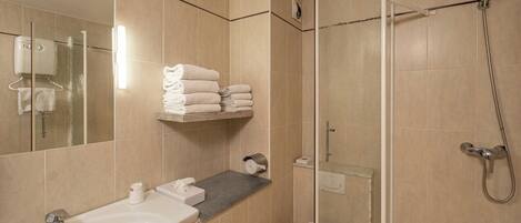 A bathroom with a sink, mirror, towel rack, shower, and toilet.