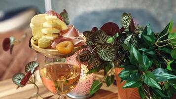 A glass of white wine on a wooden table with a decorative plate of food and a potted plant.