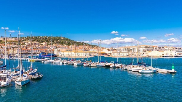 A marina with numerous boats docked, a green lighthouse, and a coastal town with buildings. - The Originals City Hotel Hippocampe Sète Balaruc (Balaruc-le-Vieux)