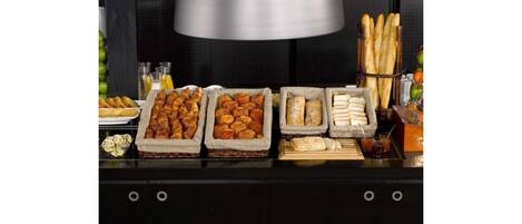 A buffet table with various baked goods and fruits.