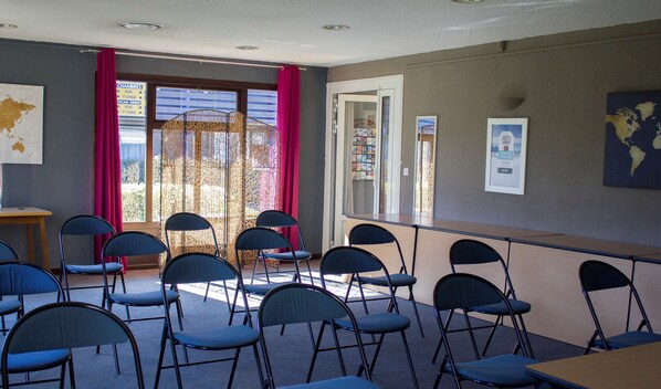 A conference room with foldable chairs, a long table, and a view of a building through large windows.