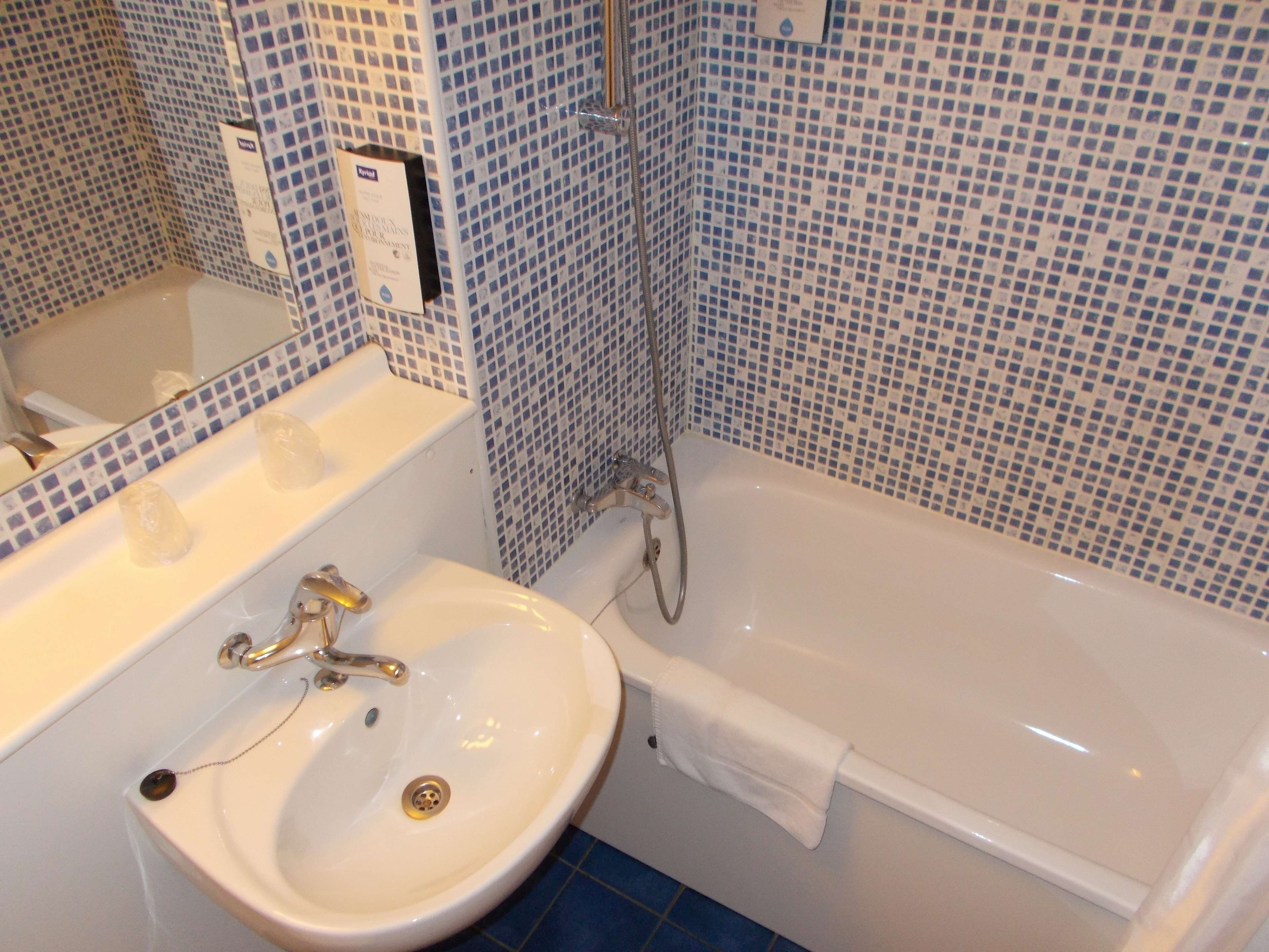 A bathroom with a white sink, a mirror, and a bathtub.