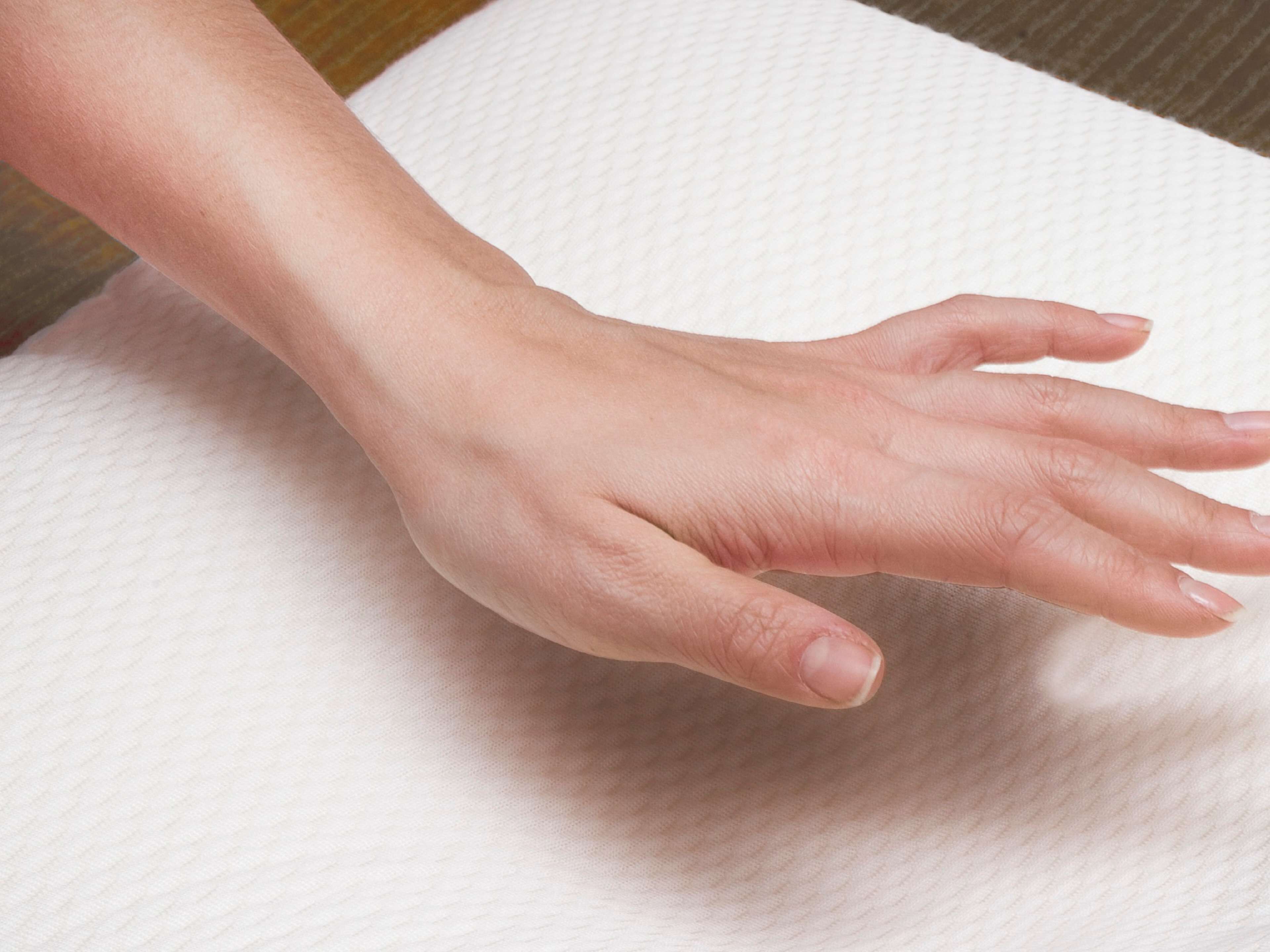 A hand resting on a textured white surface.