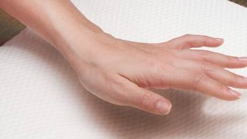 A hand resting on a textured white surface.