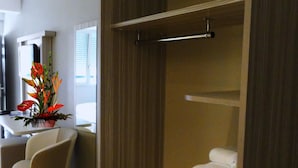 A hotel room with a bed, a small table with a vase of flowers, a chair, and a window with blinds.