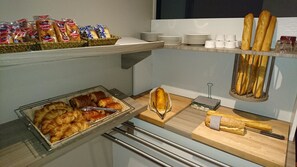 A buffet area with various baked goods, including bread and pastries, and a selection of cheeses. - Hotel Kyriad Toulouse Sud - Roques (Roques)