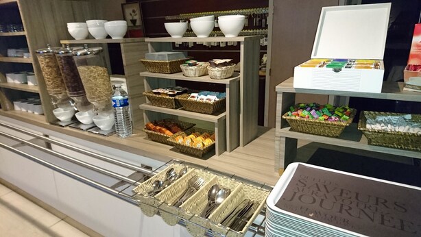 A self-service breakfast area with various food items, utensils, and a water dispenser.