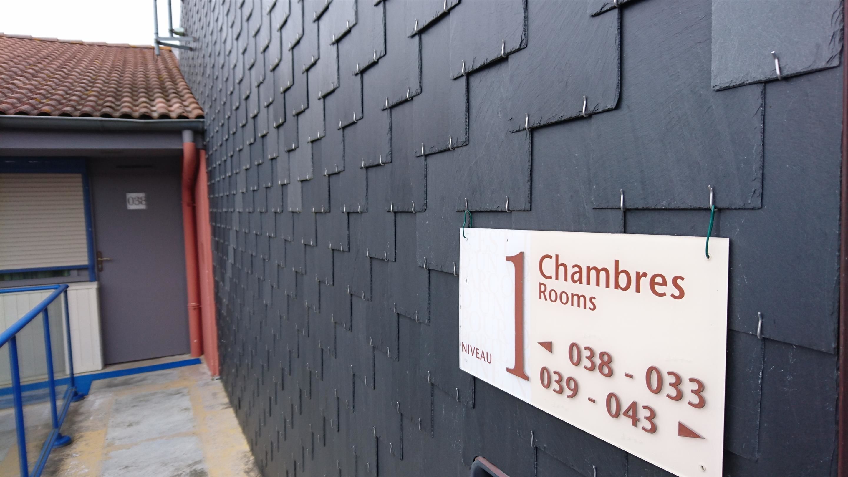 A sign for 'Chambres Rooms' with contact numbers.