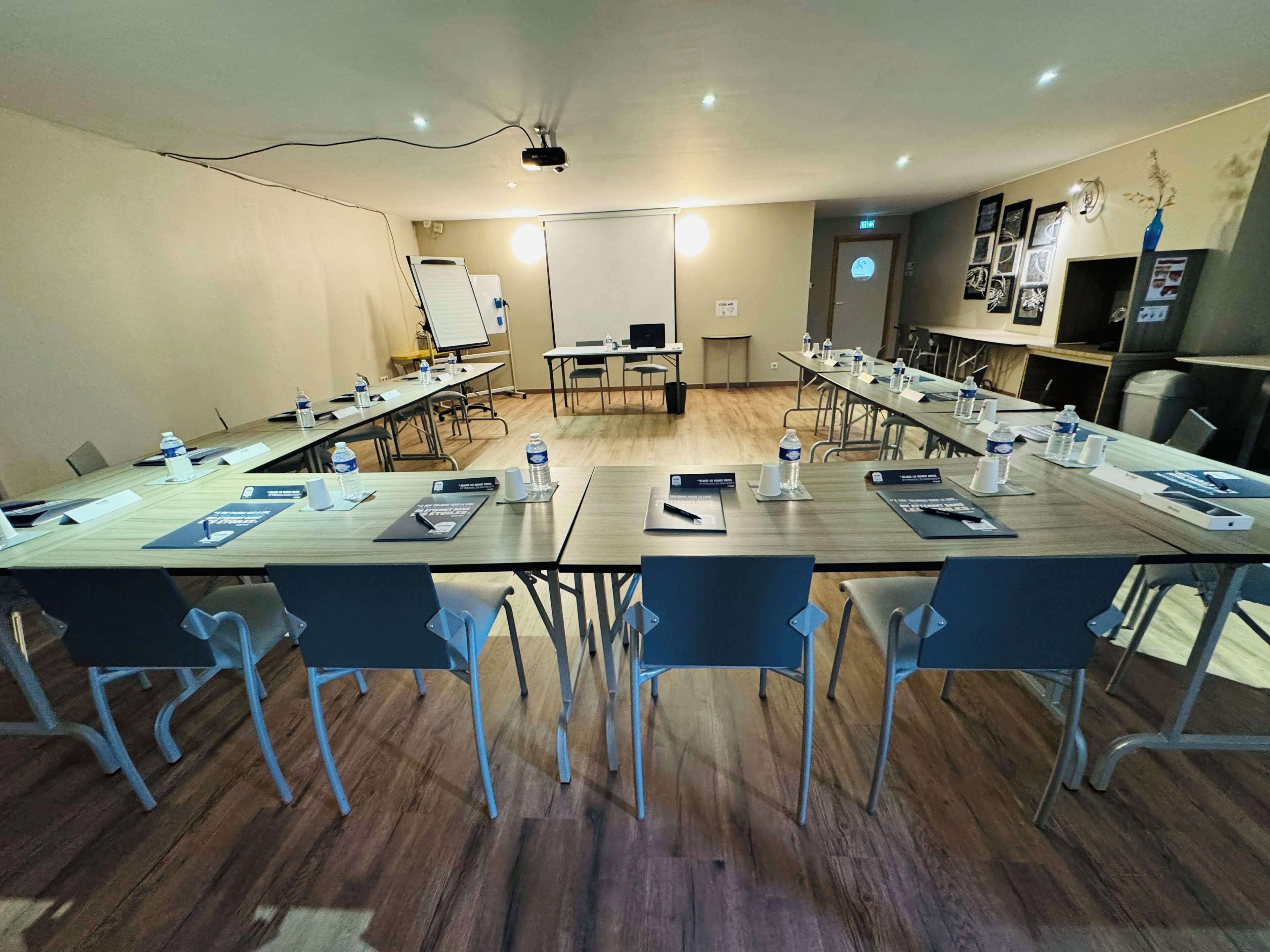 A conference room with a long table, chairs, nameplates, water bottles, and a whiteboard.