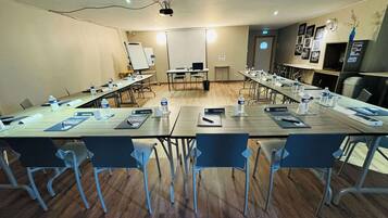 A conference room with a long table, chairs, nameplates, water bottles, and a whiteboard.