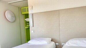 Habitación de hotel con dos camas individuales, una pared verde y un techo blanco.