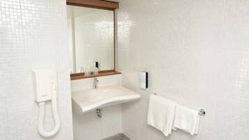 Un baño moderno con un lavamanos blanco, un espejo y un perchero para toallas.