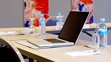 A conference room with a laptop on a table, water bottles, and a glass pitcher.