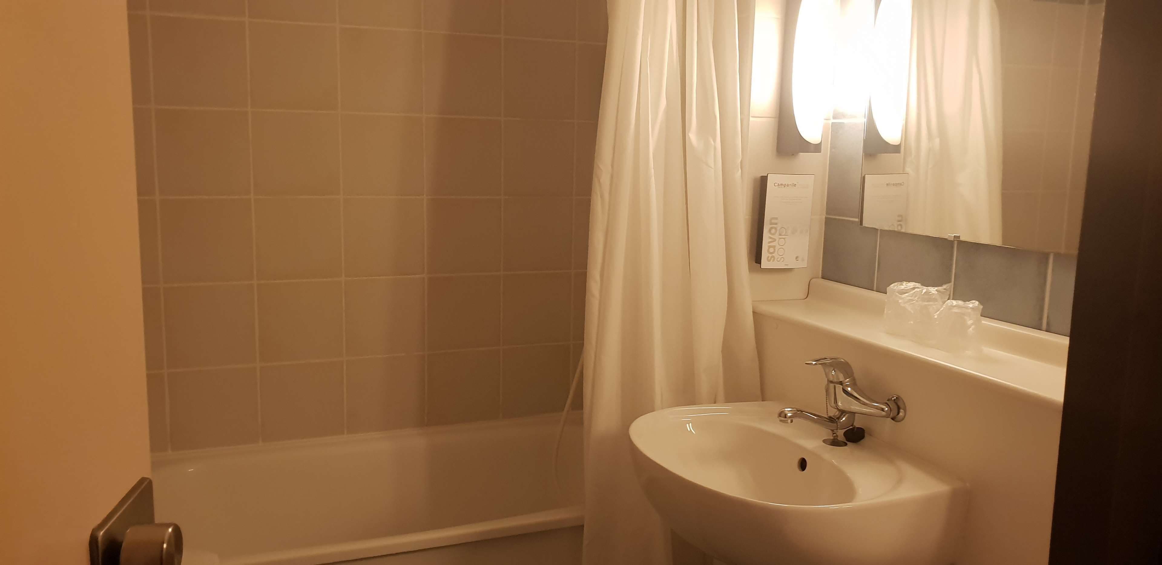 Ein Badezimmer mit Dusche, Waschbecken und Spiegel.
