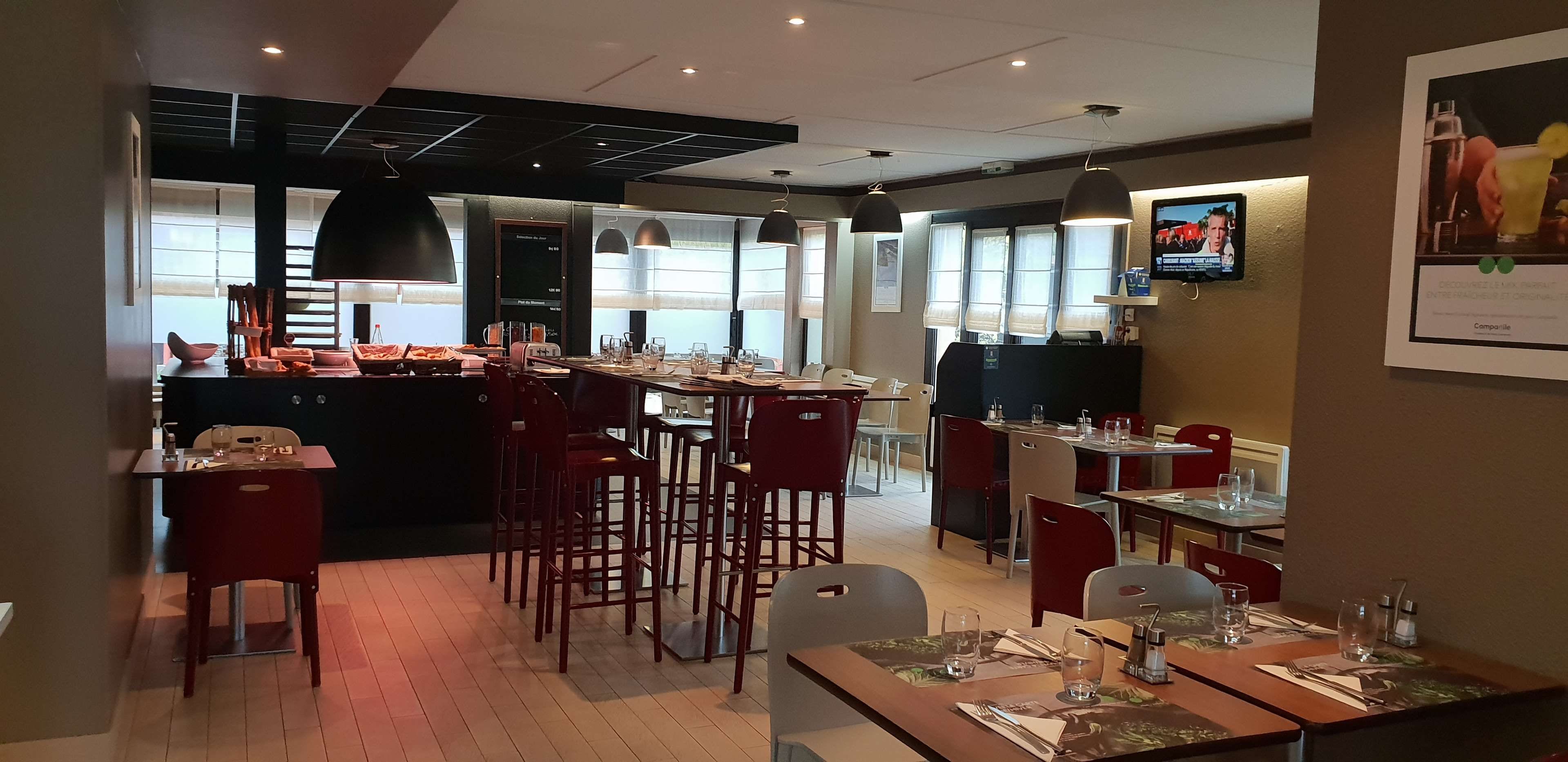 A restaurant with a bar area, multiple seating options, and a television screen on the wall.