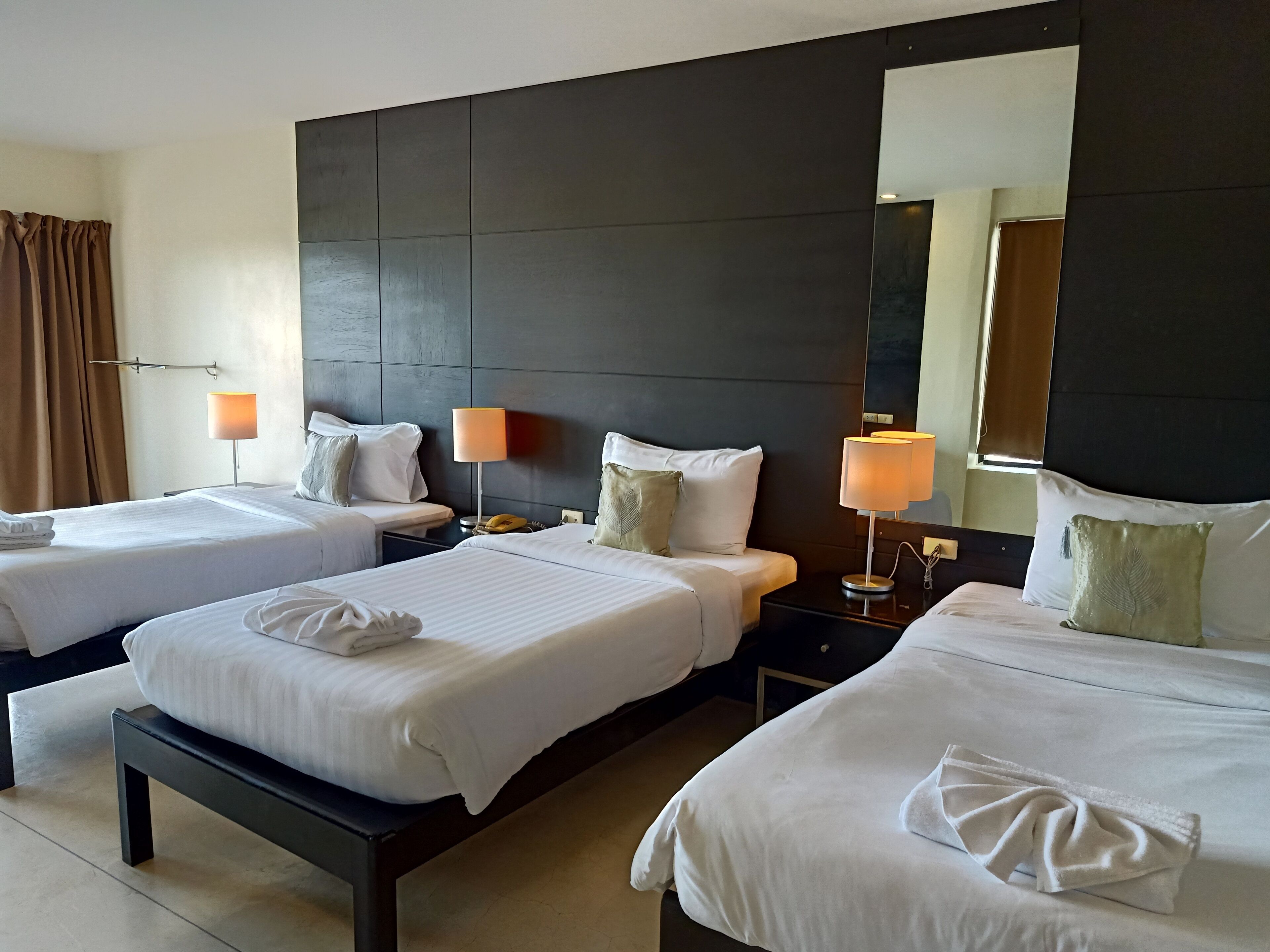 A hotel room with two beds, a large mirror, and two bedside lamps.
