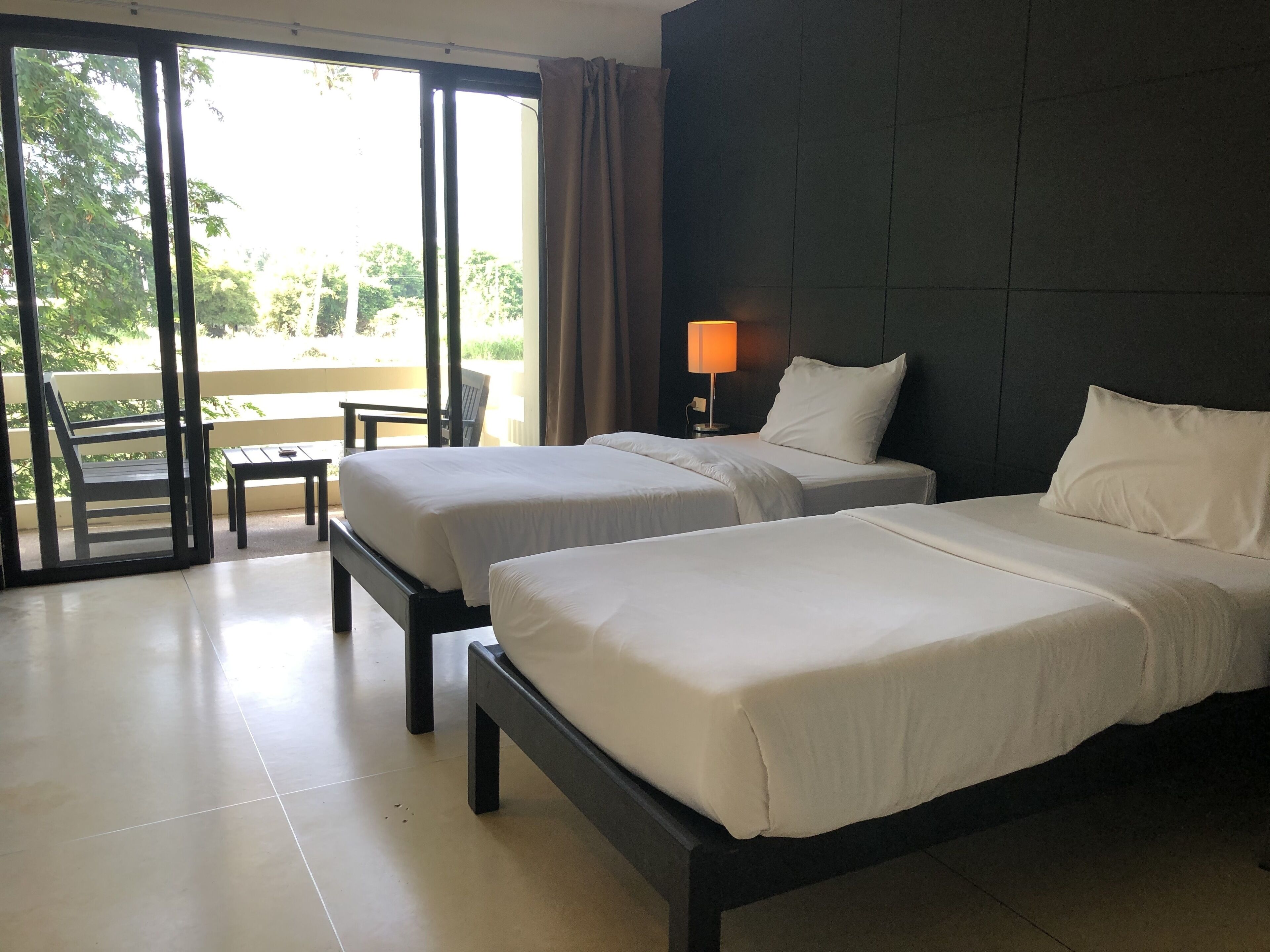 Habitación de hotel con dos camas, una mesa, una silla y vistas al exterior.