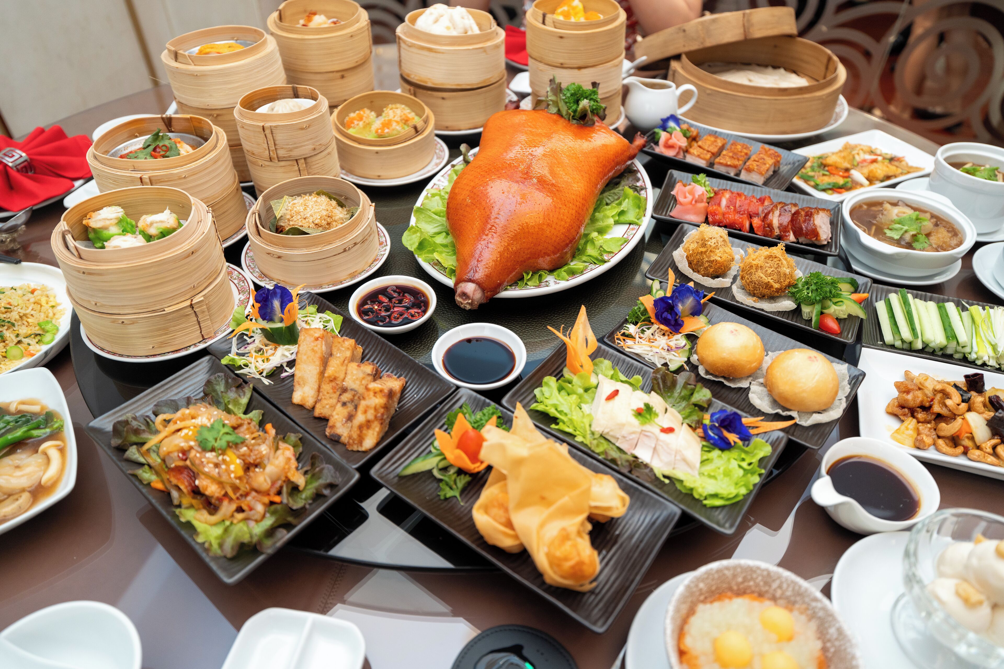 Een tafel met diverse gerechten, waaronder een hele gebraden varken, verschillende soorten dumplings en diverse bijgerechten.