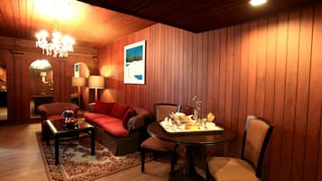 Une pièce chaleureuse avec un mur lambrissé en bois, un canapé rouge, une table à manger avec des chaises et un lustre.