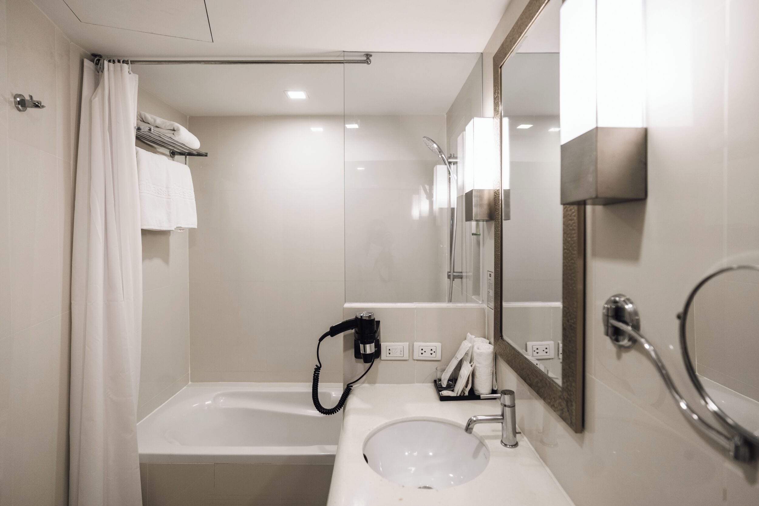 Une salle de bain moderne équipée d’une baignoire, d’un lavabo, d’un miroir et d’un porte-serviettes.