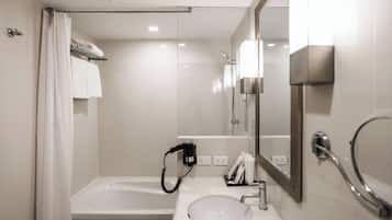 Une salle de bain moderne équipée d’une baignoire, d’un lavabo, d’un miroir et d’un porte-serviettes.