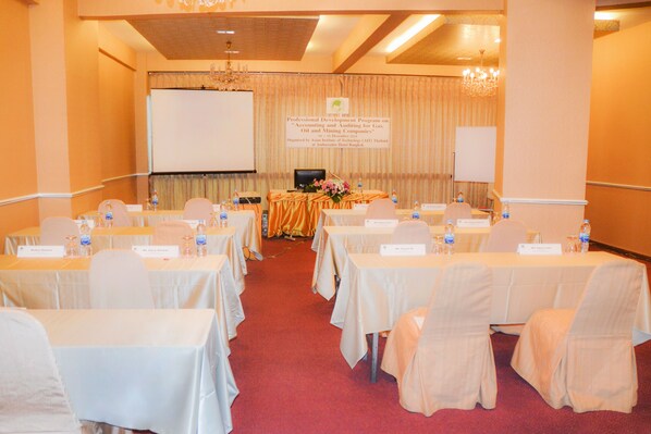 A conference room with tables set for a meeting, nameplates, and a presentation screen. - Ambassador Bangkok Hotel (Bangkok)