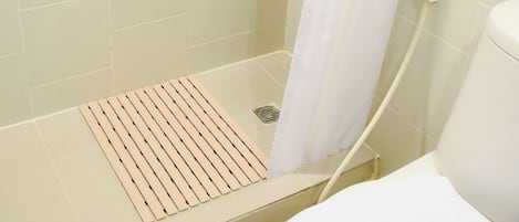 Un espace douche avec un rideau de douche blanc, une serviette blanche et un distributeur de savon blanc fixé au mur.