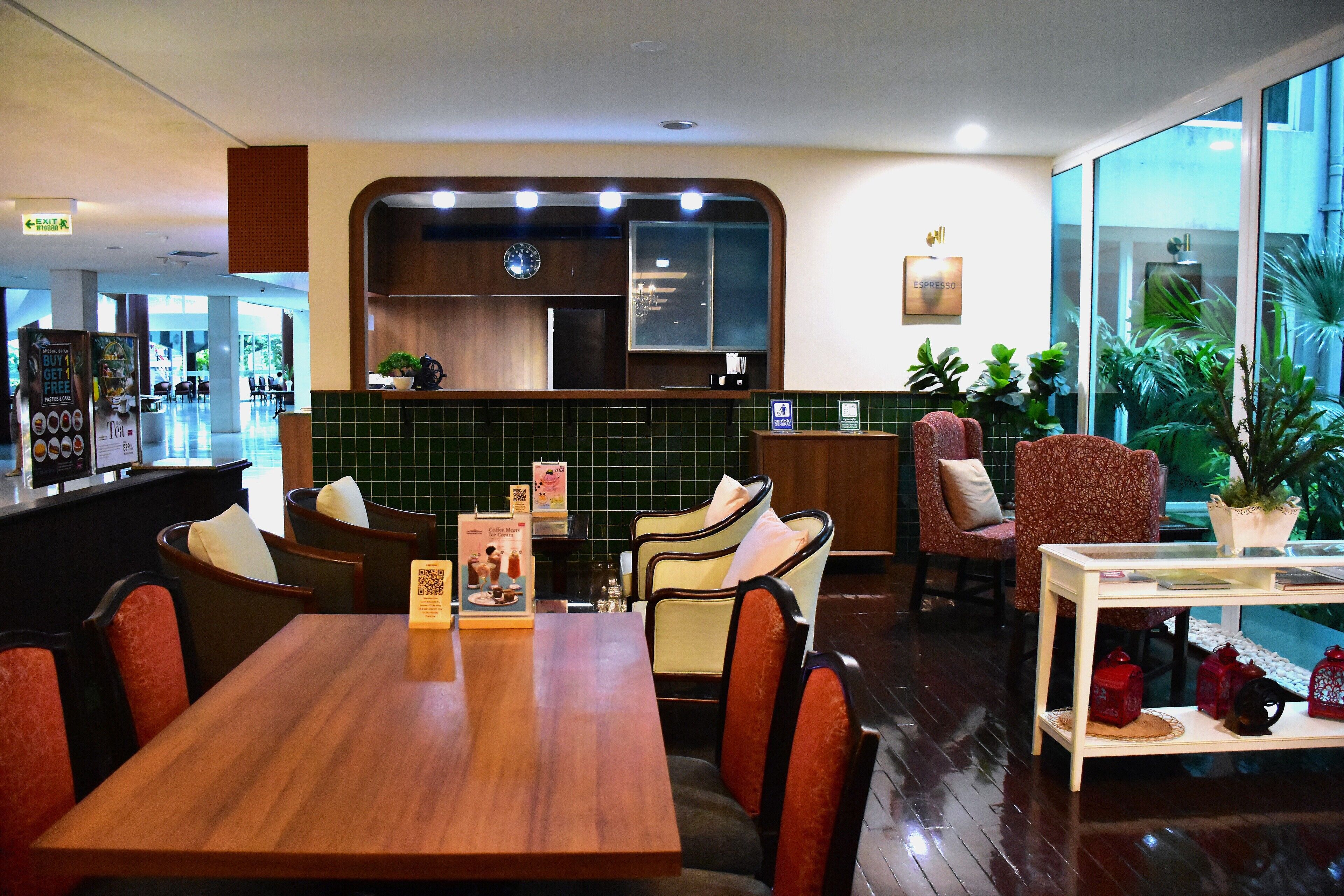 A restaurant with a wooden table and chairs, a counter, and a view of the outside.