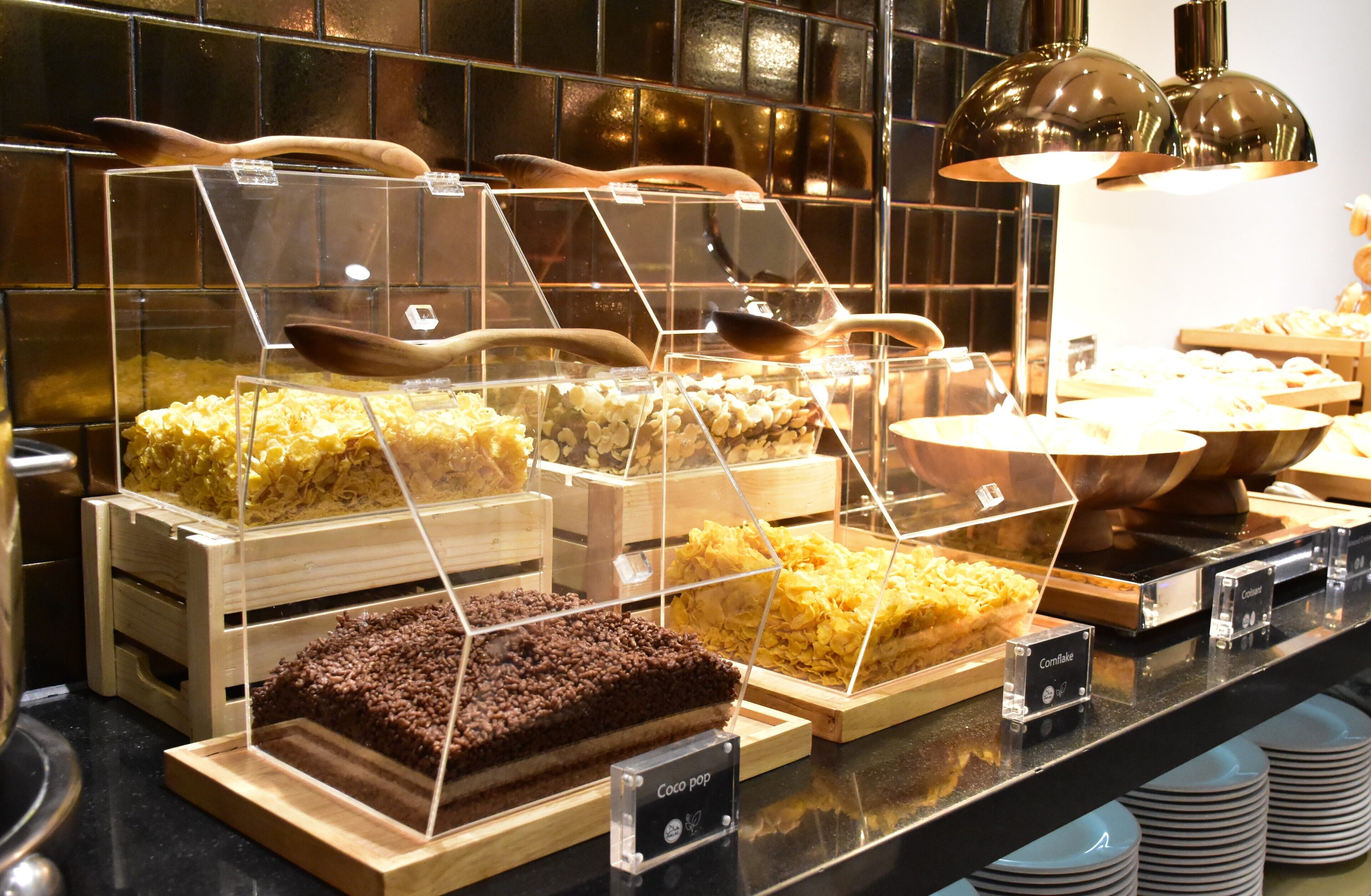A dessert display with various types of cakes and pastries in clear containers, each labeled with its name.