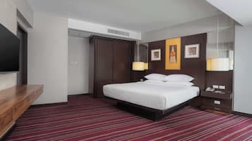 Habitación de hotel con cama, escritorio, televisor de pantalla plana, armario y espejo.