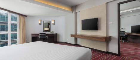 Une chambre d’hôtel avec un grand lit, un bureau, une chaise, un téléviseur à écran plat fixé au mur et un grand miroir.