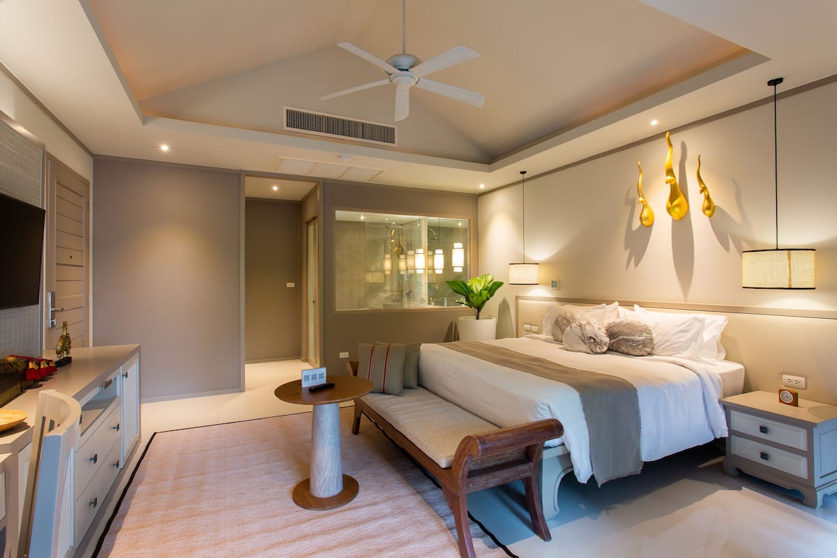 Une chambre moderne avec un lit, des tables de chevet, un bureau et un ventilateur de plafond.
