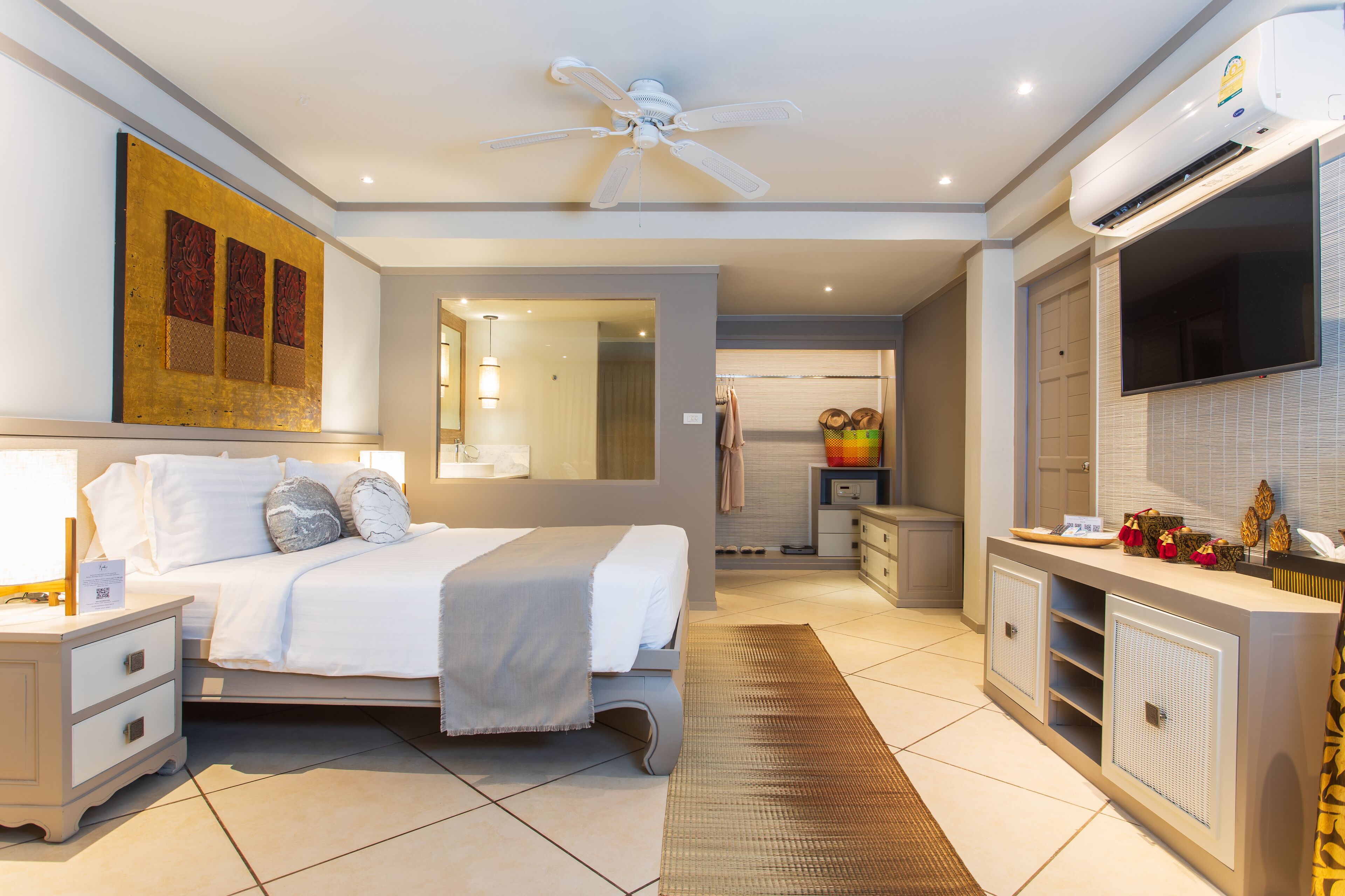 A modern hotel room with a bed, a vanity with a mirror, a television, and a ceiling fan.