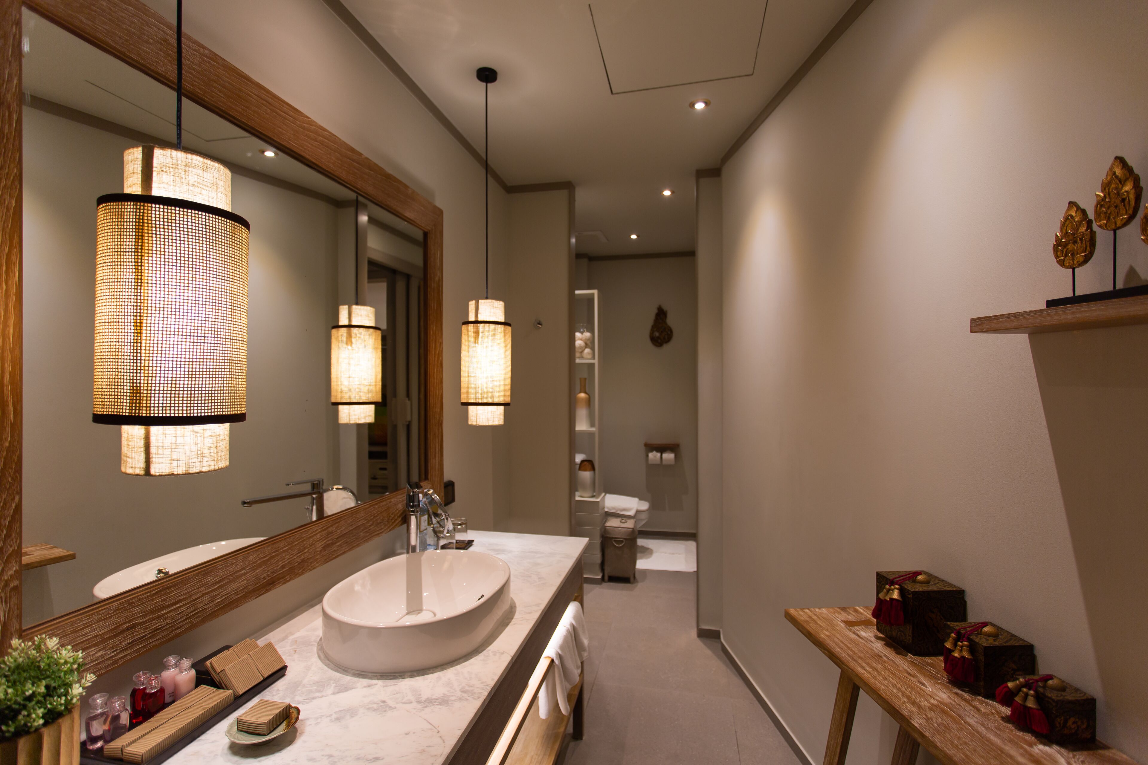 A modern bathroom with a large mirror, a round sink, and two pendant lights.