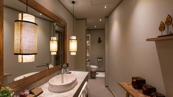 A modern bathroom with a large mirror, a round sink, and two pendant lights.
